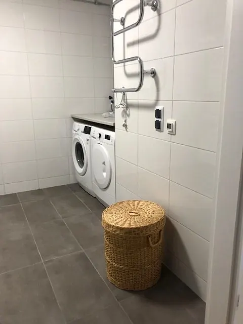 Kaklat badrum med tvättmaskin och torktumlare, handdukstork och tvättkorg