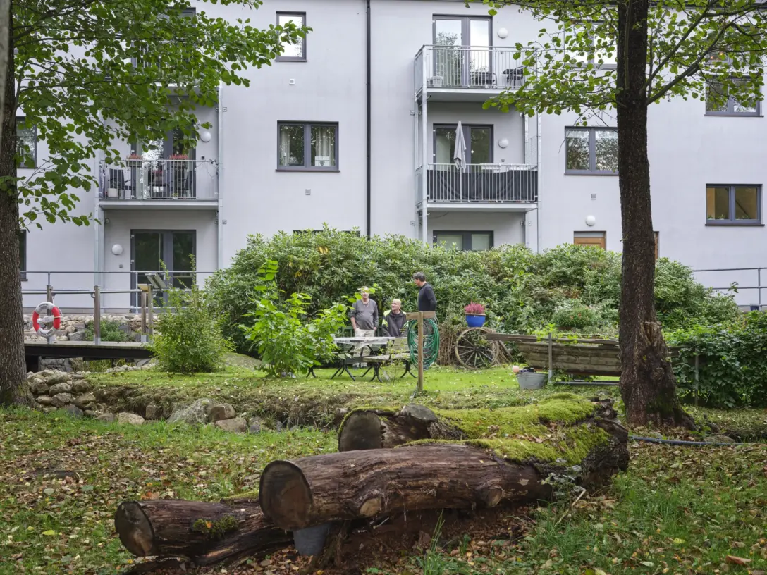 Granitens trädgård med grönska och sittplatser framför huset